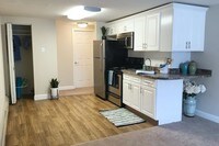 Newly remodeled kitchen in our Sunrise floor plan featuring granite-style countertops, wood-style flooring, and ample cabinet space. - Country Manor Apartments in Springfield, Massachusetts