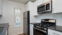Kitchen with Stainless Steel Appliances and Quartz Countertops - The Village at Del Mar Heights Apartments in San Diego, California