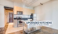Open kitchen with an island, stainless steel appliances and granite countertops in select homes - Broadway Lofts Apartamentos in San Diego, California