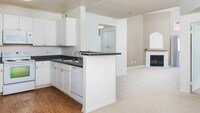 Kitchen and Carpeted Living Room with Wood-Burning Fireplace - Del Mar Ridge Apartamentos in San Diego, California