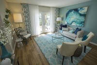 Spacious living room featuring wood-style flooring and doors to your very own private patio. - The Bentley at Maitland Apartments in Orlando, Florida
