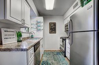 Kitchens featuring updated counter tops and cabinetry, dishwasher, and cutout to living area. - Domain 3201 Apartments in Tucson, Arizona